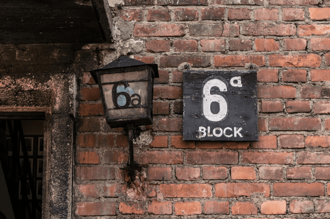 Zdjęcie znaku oraz latarni na budynku bloku 6 a z obozie. 