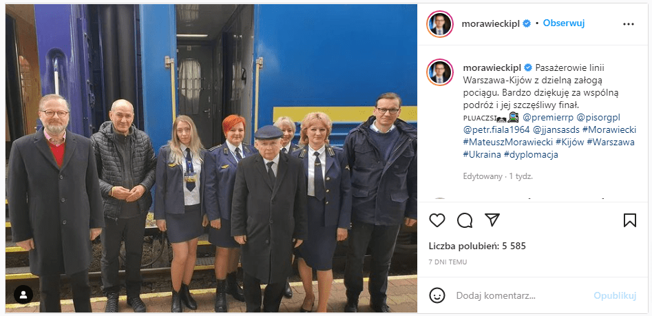 Zrzut ekranu zdjęcia delegacji udającej się do Kijowa oraz załogi pociągu na tle niebieskiego wagonu.