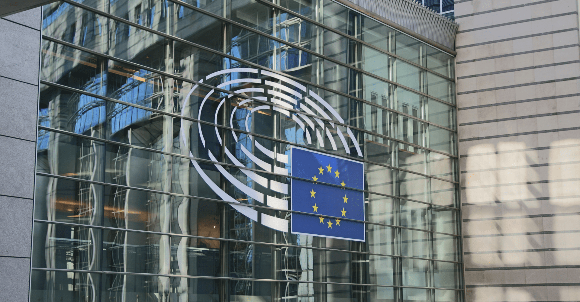 Szklany budynek z logotypem parlamentu europejskiego.