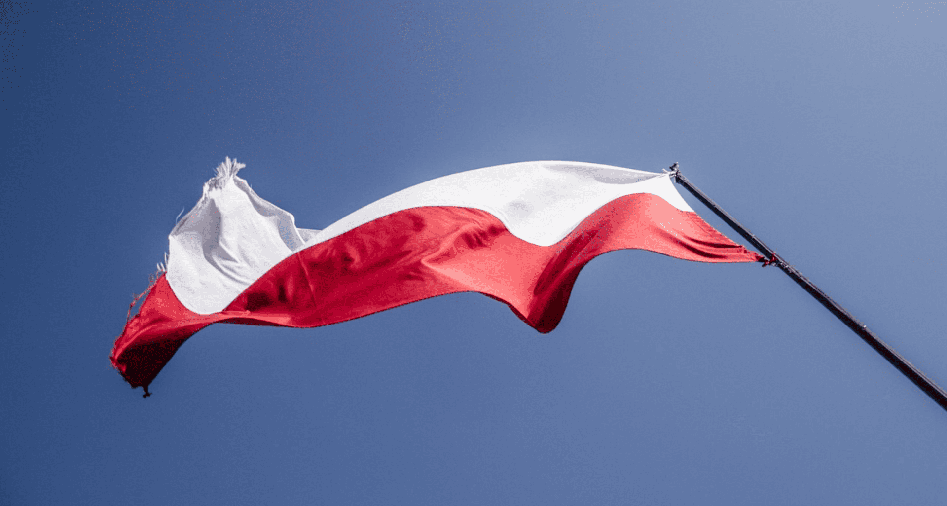 Biało-czerwona flaga Polski na tle błękitnego nieba