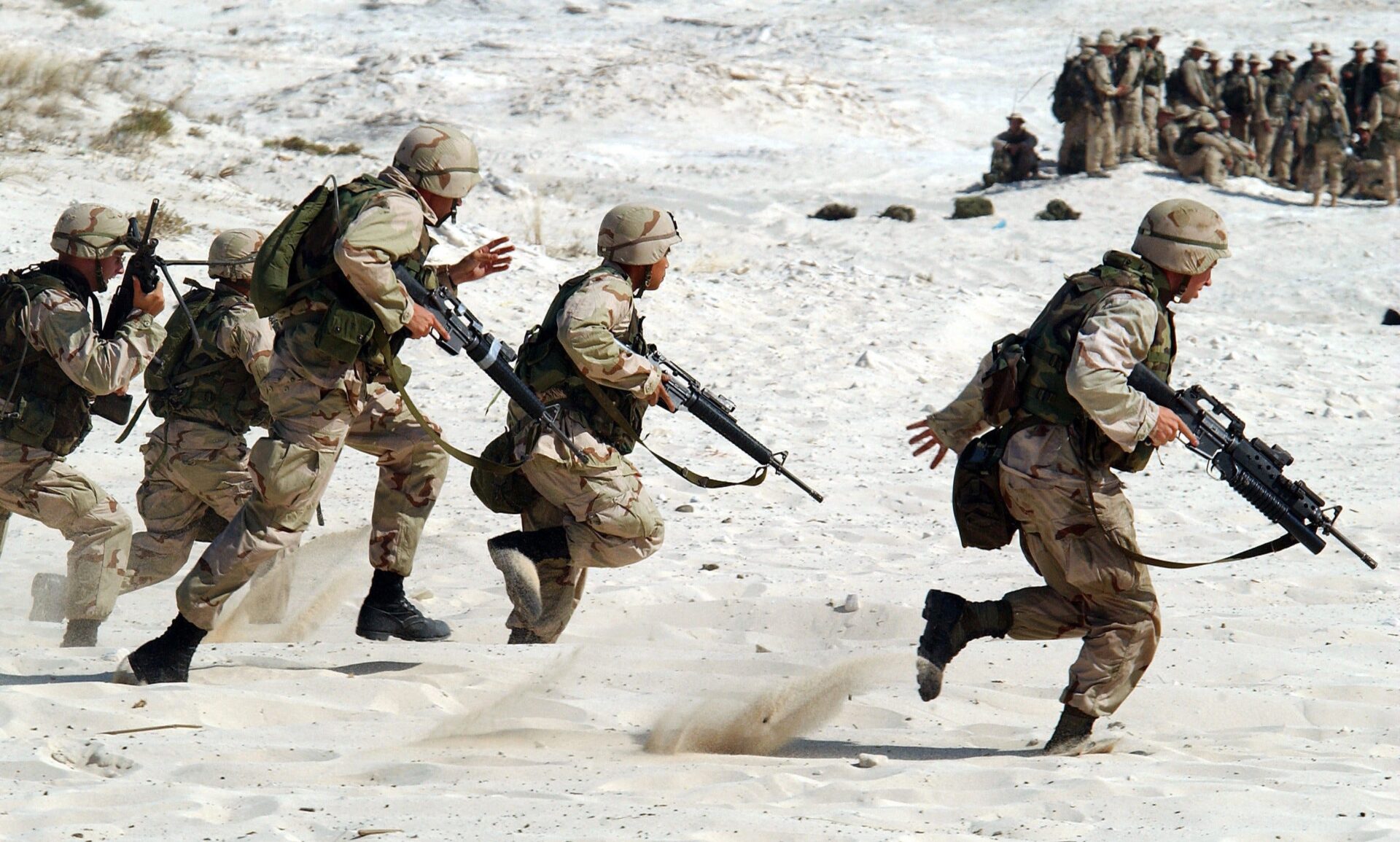Żołnierze biegnący po piasku.