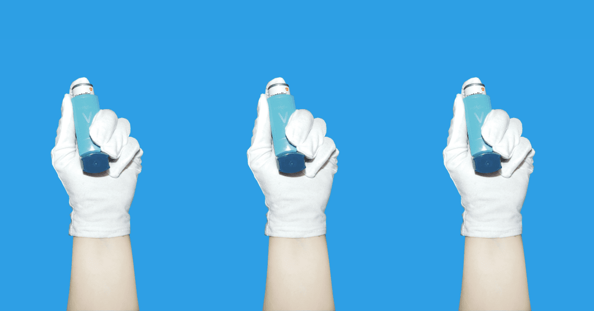 Ręka lekarza na niebieskim tle trzymająca inhalator.