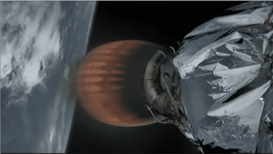Na grafice widoczna jest część rakiety Falcon 9 w trakcie lotu w kosmos. Po lewej stronie znajduje się planeta Ziemia, od której rakieta się oddala. Silnik rakiety jest rozgrzany do czerwoności. Na jego powierzchni widzimy dokładnie elementy i komponenty, takie jak przewody. Na silniku znajduje się mały niezidentyfikowany obiekt o owalnym kształcie.