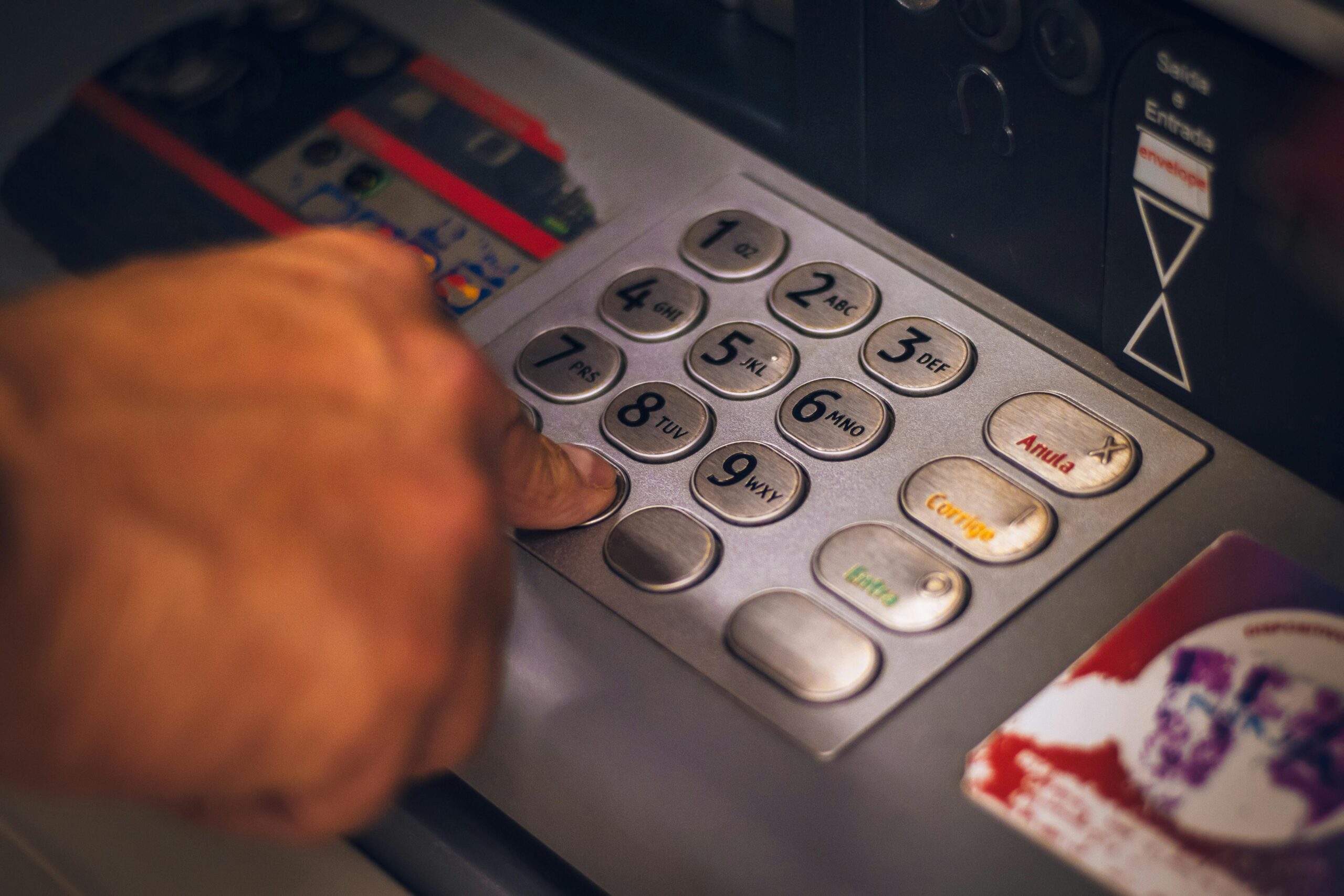 Dłoń klikająca w guziki bankomatu