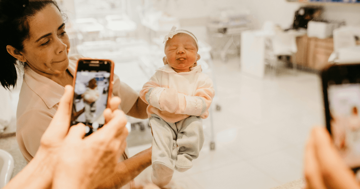 noworodek trzymany przez kobietę, telefony robiące zdjęcia