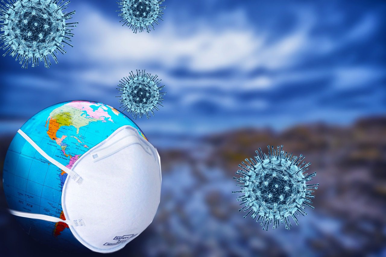 Kolaż – 4 komórki niebieskie wirusów, w lewym dolnym rogu globus z założoną maseczką.