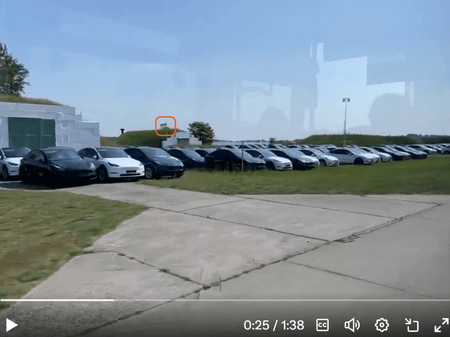 Zrzut ekranu filmu z samochodami marki Tesla. Zaznaczona jest niemiecka flaga widoczna na nagraniu.