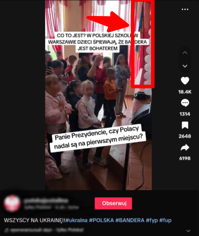 На скріншоті з TikTok видно групу дітей, які стоять у залі біля сцени та співають. На задньому плані видно прапор та прикраси.